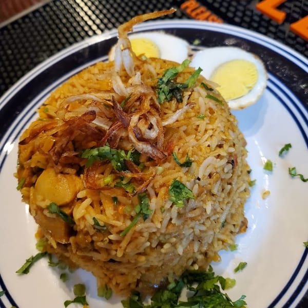 Bombay Social's chicken biryani with fried onions, cilantro, and two hard-boiled egg halves.